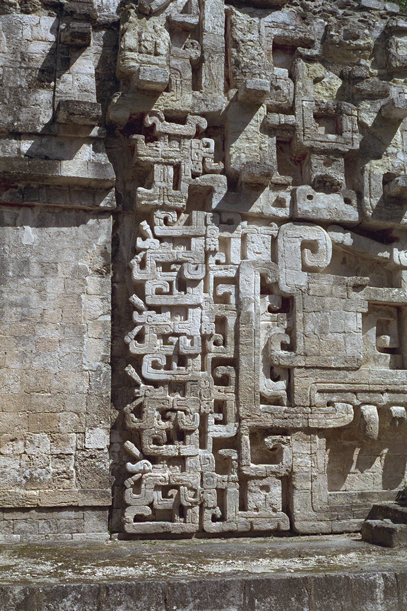 Detail of the vertical stack of abstract profile serpent masks on the building's edge