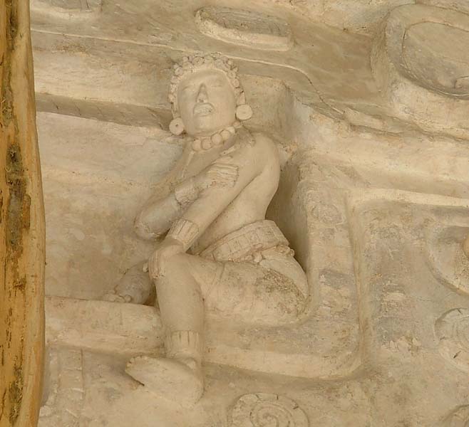 Chenes zoomorphic entrance, closeup of small figure sitting on monster's right eyelid.